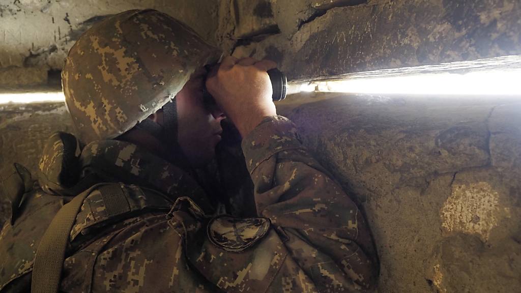 dpatopbilder - Ein armenischer Soldat blickt in einem Unterschlupf an der Front in Richtung der aserbaidschanischen Stellungen. Foto: -/AP/dpa