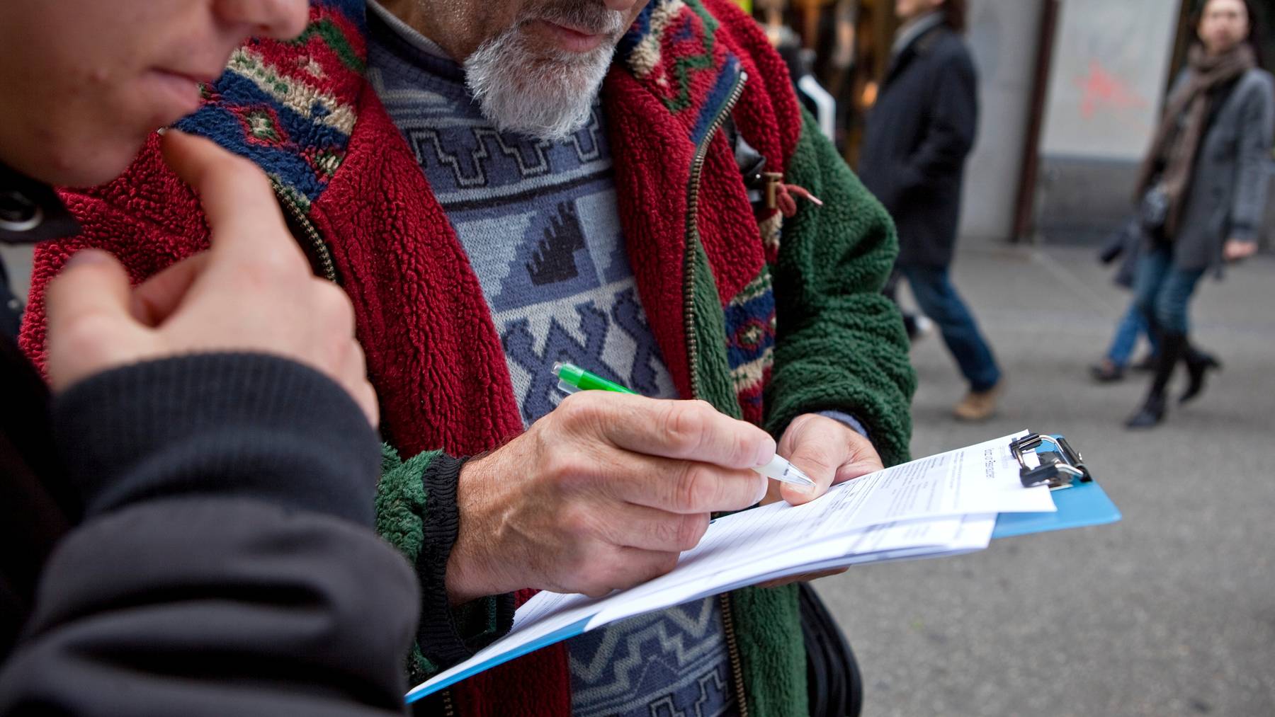 Passantinnen und Passanten unterschreiben in einer Fussgängerzone eine Volksinitiative. (Symbolbild)