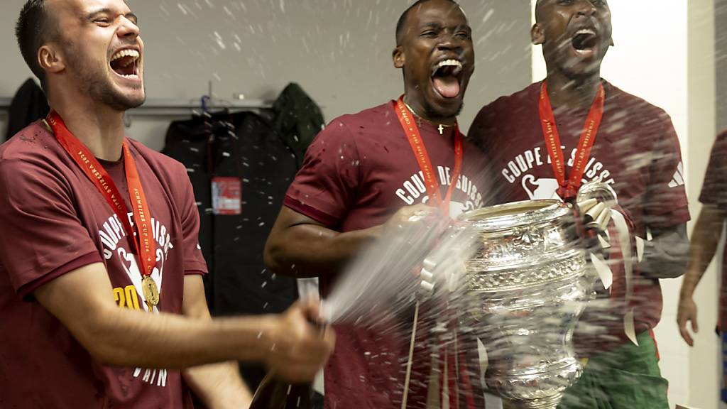 Die Servette-Spieler Jérémy Guillemenot (links), Dereck Kutesa (Mitte) und Gaël Ondoua jubeln mit der gewonnenen Cup-Trophäe