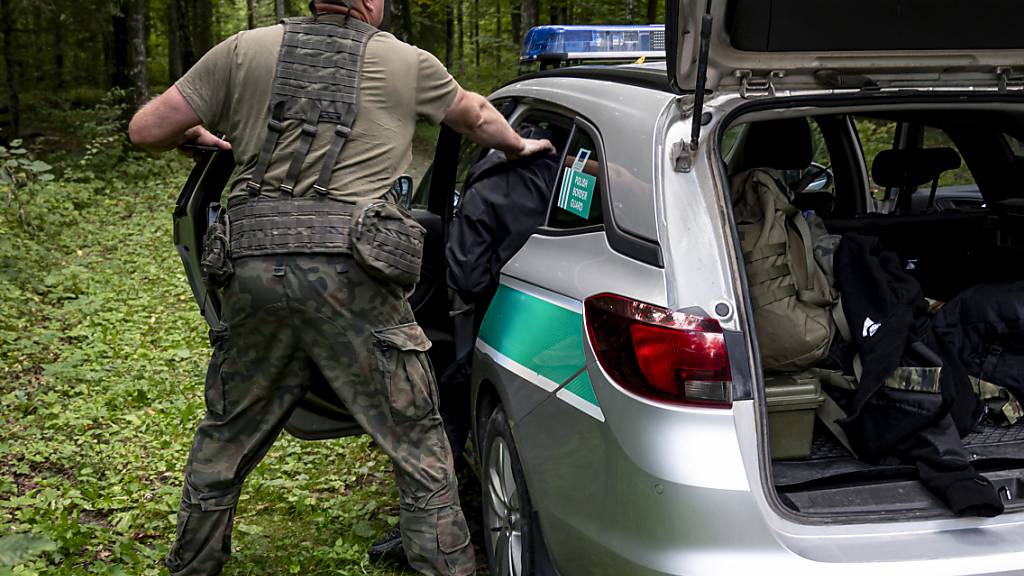 ARCHIV - Ein polnischer Grenzschützer nimmt im Grenzgebiet zu Belarus einen Mann fest. An der EU-Außengrenze zum Nachbarland Belarus hat Polen einen 5,5 Meter hohen Metallzaun mit Bewegungsmeldern und Nachtsichtkameras errichtet. In den vergangenen Monaten hat Polens Grenzschutz wieder eine steigende Zahl von Migranten beobachtet. Foto: Fabian Sommer/dpa