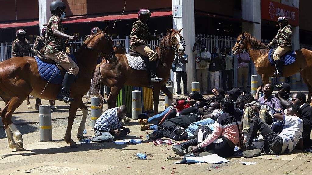 Polizisten auf Pferden umzingeln Demonstranten bei Protesten gegen Entführungen. Foto: Andrew Kasuku/AP/dpa