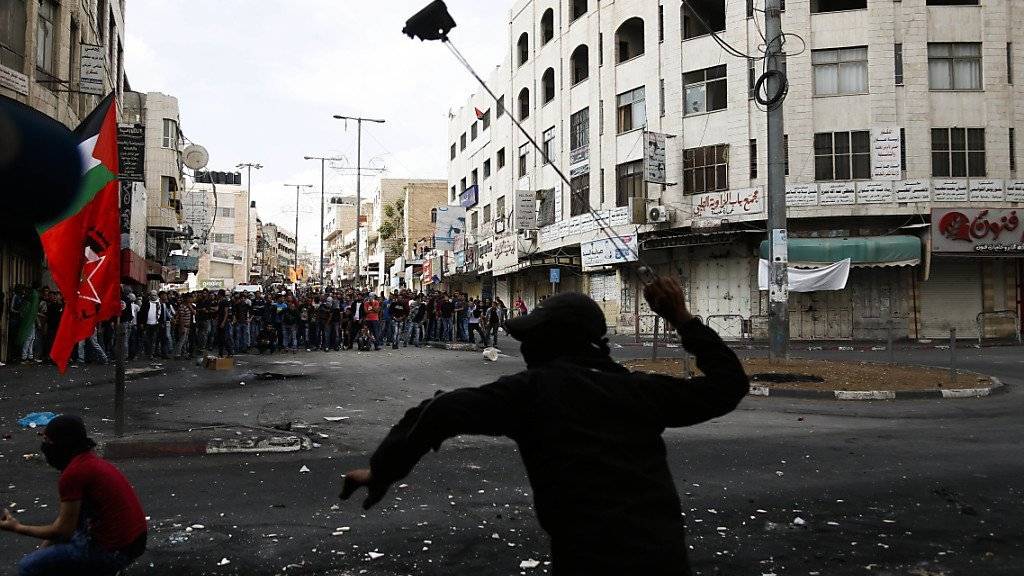 Ein palästinensischer Jugendlicher schleudert einen Stein gegen israelische Soldaten in Hebron.