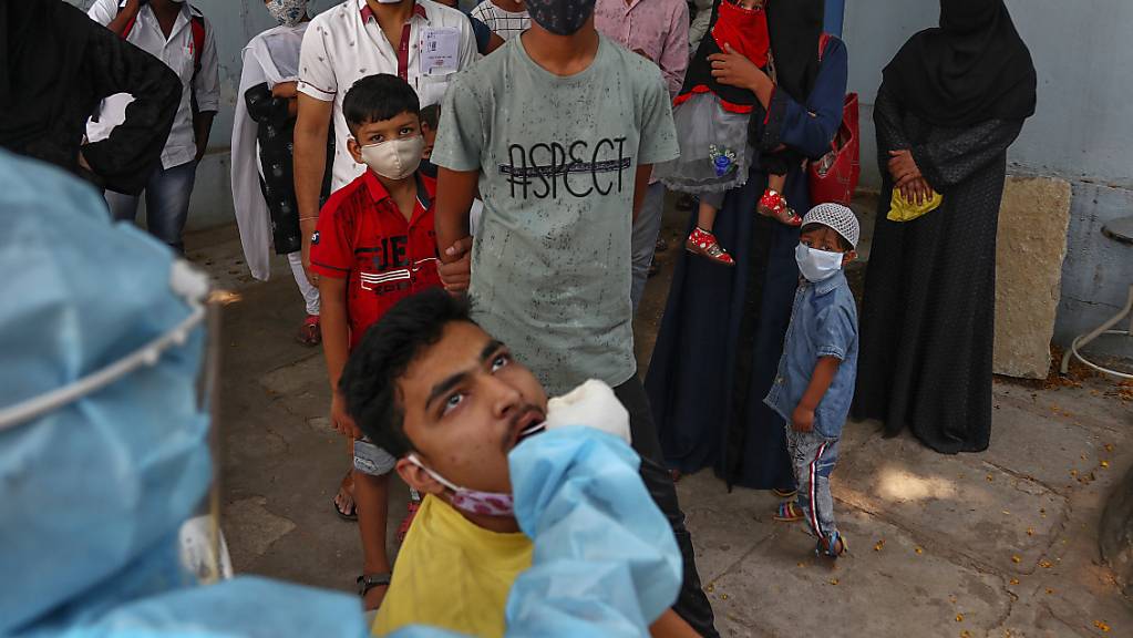 Ein Mitarbeiter des Gesundheitswesens in Indien nimmt eine Nasenabstrichprobe eines Mannes für einen Coronatest. Foto: Mahesh Kumar A./AP/dpa