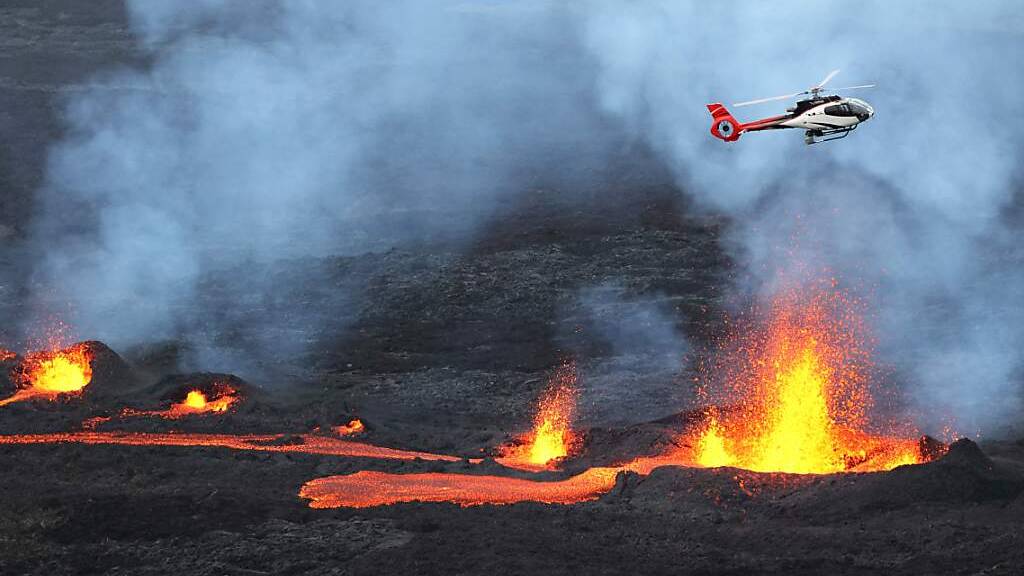 dpatopbilder - Ein Hubschrauber fliegt über dem ausbrechenden Vulkan Piton de la Fournaise auf der französischen Insel Reunion im Indischen Ozean. (Archivbild) Foto: Richard Bouhet/AFP/dpa