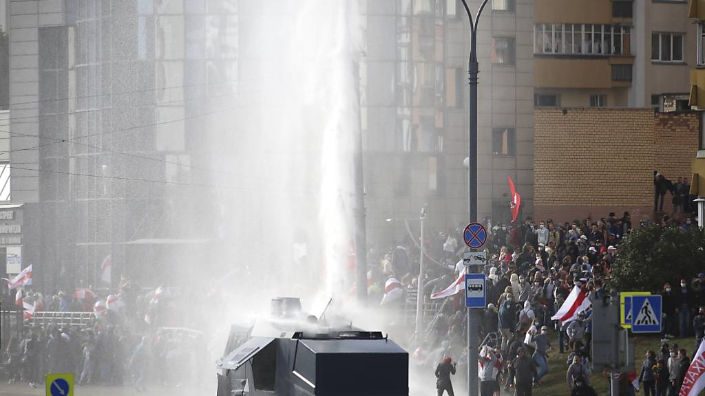 Polizisten setzten einen Wasserwerfer gegen Demonstranten ein. Trotz eines Großaufgebots an Sicherheitskräften haben Zehntausende Menschen gegen den autoritären Staatschef Lukaschenko demonstriert. Foto: Uncredited/AP/dpa