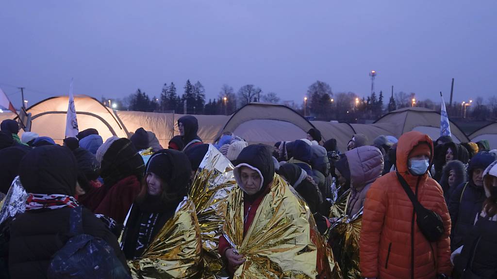 Flüchtlinge warten in einer Menschenmenge auf den Transport, nachdem sie aus der Ukraine geflohen sind und am Grenzübergang in Medyka, Polen, angekommen sind. Foto: Markus Schreiber/AP/dpa