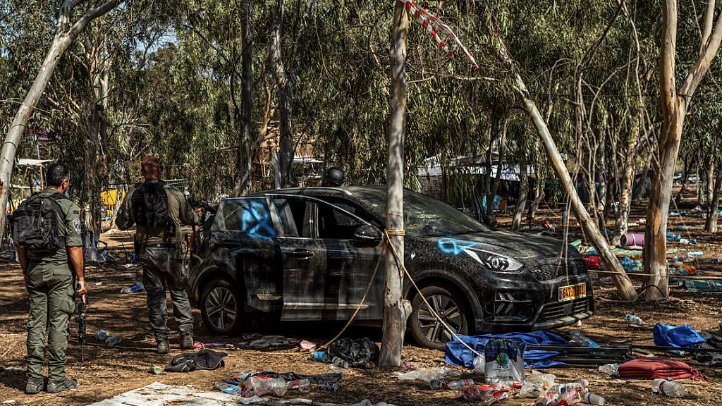Israelische Soldaten stehen neben einem verlassenen Auto auf dem Gelände des Supernova-Wüstenmusikfestivals. Angreifer der im Gazastreifen herrschenden Islamistenorganisation Hamas hatten Hunderte Menschen auf dem Festival getötet und viele weitere als Geiseln verschleppt. Foto: Ilia Yefimovich/dpa