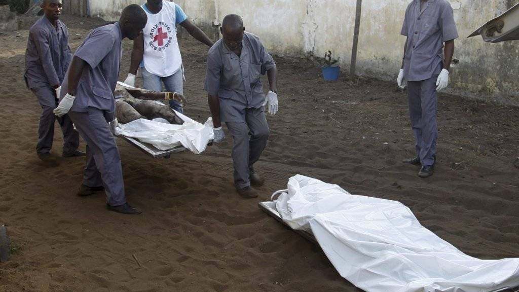 Polizisten und Helfer in der Elfenbeinküste tragen Opfer der Anschläge von Grand-Bassam weg.