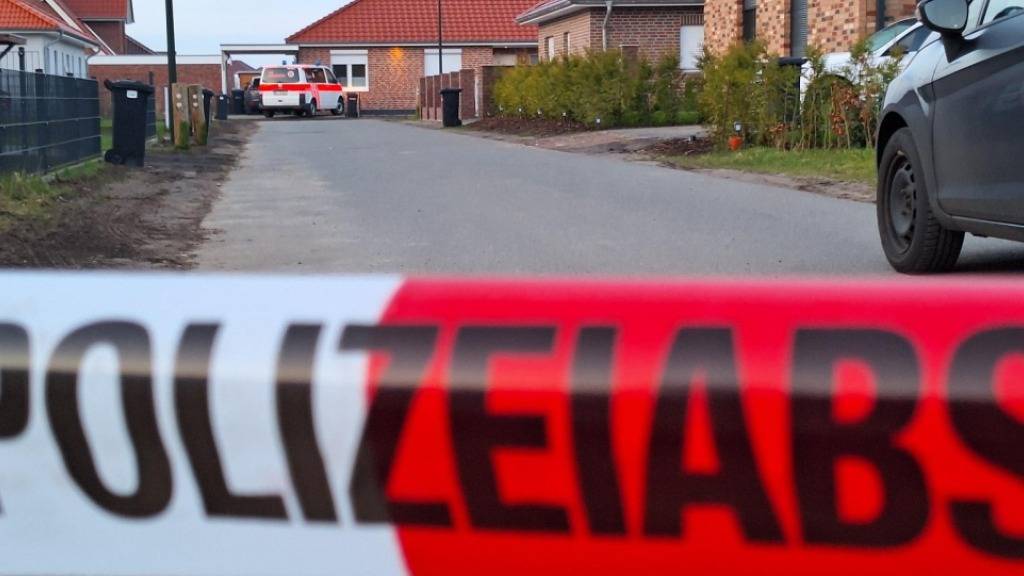 Einsatzkräfte stehen hinter einem Absperrband in Bothel, Deutschland. Foto: Kai Moorschlatt/NordwestMedia TV/dpa