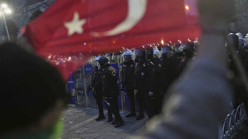 Ein Demonstrant hält eine türkische Flagge, während Bereitschaftspolizisten während einer Demonstration nach der Verhaftung und Inhaftierung des Istanbuler Bürgermeisters Ekrem Imamoglu Wache stehen. Foto: Francisco Seco/AP/dpa