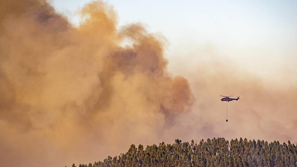 Ein Hubschrauber über den Rauchschwaden eines  Waldbrandes in der Gemeinde Almonaster la Real. Foto: A. Perez/Europa Press/AP/dpa