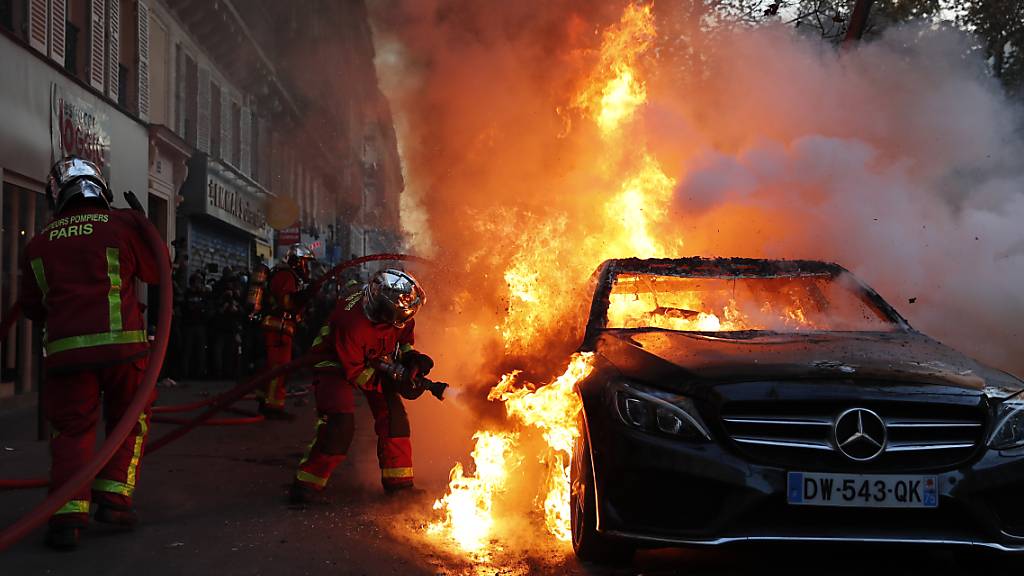 Die Feuerwehr löscht ein brennendes Auto in Paris. Foto: Francois Mori/AP/dpa