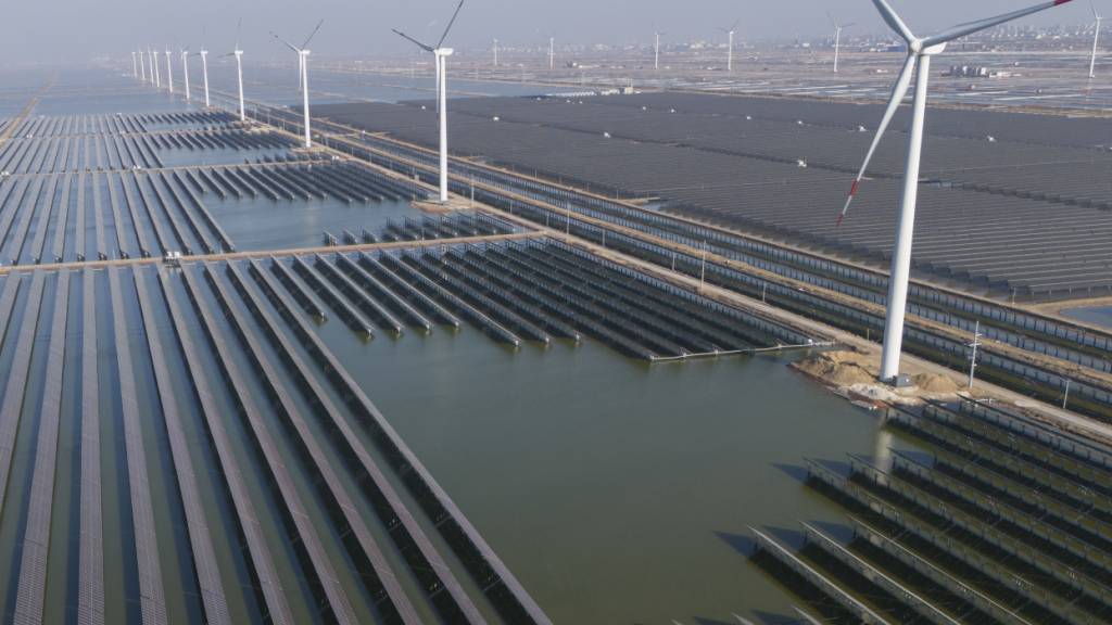 ARCHIV - Windturbinen säumen die Küstenlinie entlang eines riesigen Solarparks. Foto: Ng Han Guan/AP/dpa