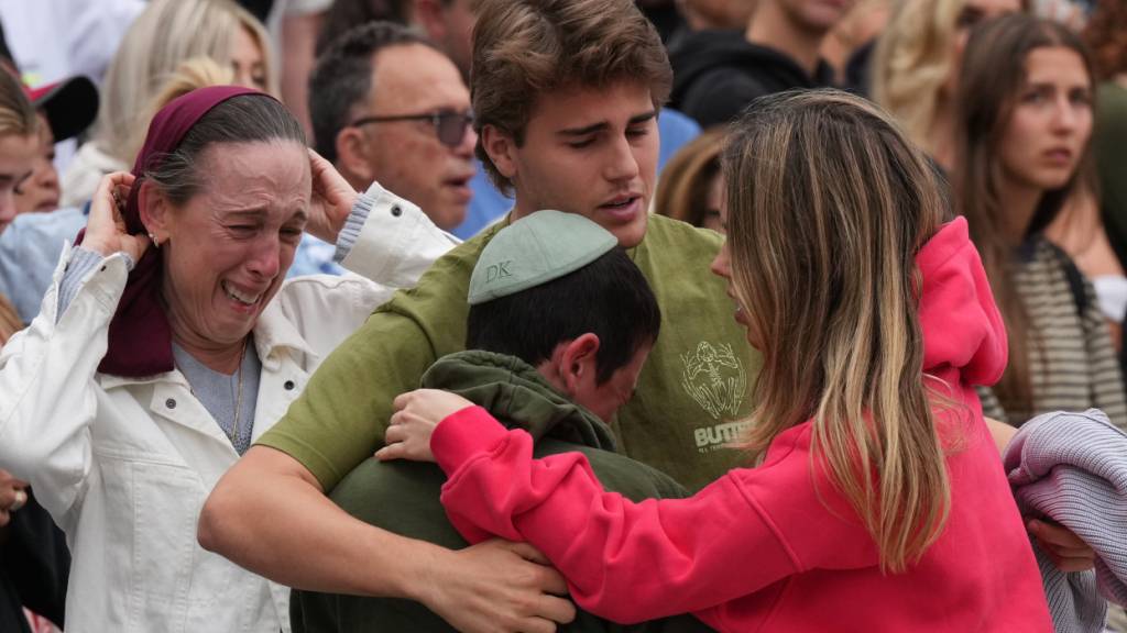 Familienangehörige eines Opfers der Schießerei vom Sonntag trauern an einem Blumendenkmal, das nach dem Anschlag am Bondi Pavilion am Bondi Beach in Sydney, Australien, errichtet wurde. Foto: Mark Baker/AP/dpa