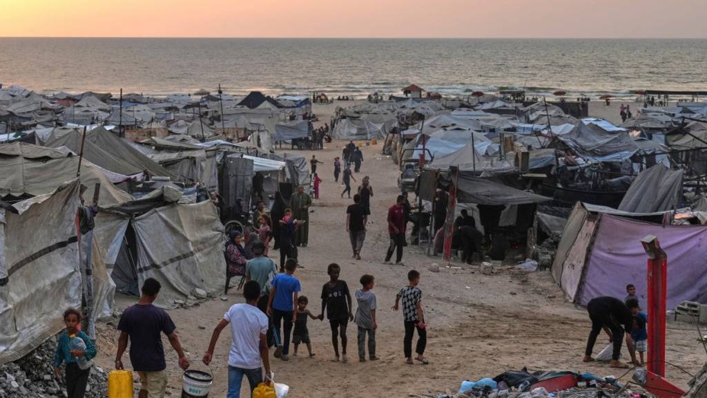 ARCHIV - Vertriebene Palästinenser gehen durch ein behelfsmäßiges Lager am Strand von Gaza-Stadt. Foto: Jehad Alshrafi/AP/dpa