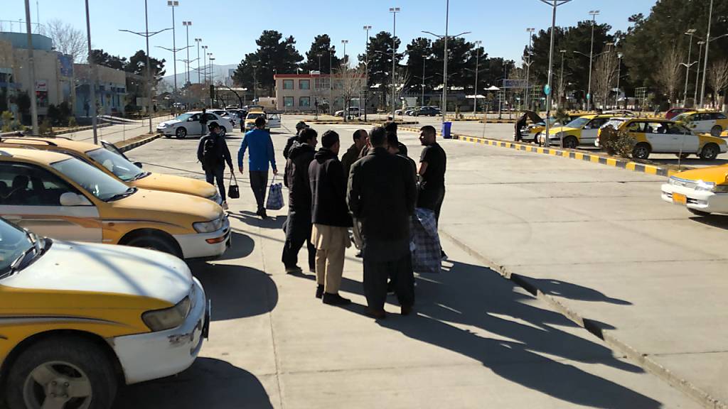 Durch einen Abschiebeflug deportierte Afghanen verhandeln vor dem Flughafen mit Taxifahrern den Preis für die Weiterreise. Nach Monaten der Unterbrechung durch die Corona-Pandemie hat Deutschland die Sammelabschiebungen nach Afghanistan wieder aufgenommen. Foto: Qiam Noori/dpa
