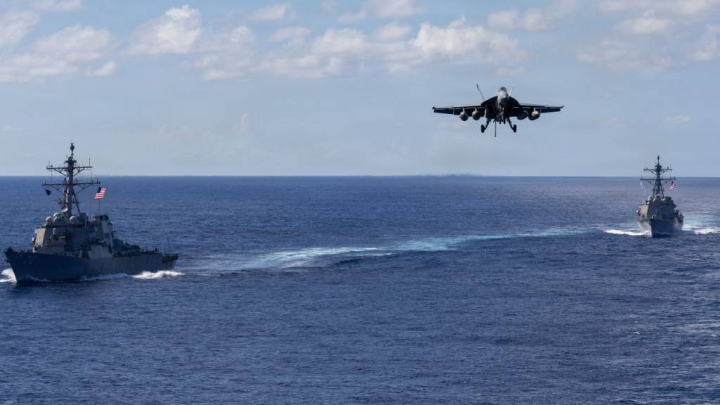 HANDOUT - Auf diesem von der Pressestelle des Pentagons zur Verfügung gestellten Bild fahren die Lenkwaffenzerstörer der Arleigh-Burke-Klasse USS Mahan (l, DDG 72) und USS Bainbridge (DDG 96) in Formation, während ein F/A-18 Super Hornet des Carrier Air Wing Eight zur Landung auf dem Flugzeugträger USS Gerald R. Ford (CVN 78) ansetzt. Foto: Petty Officer 2nd Class Triniti/U.S. Pentagon/dpa - ACHTUNG: Nur zur redaktionellen Verwendung und nur mit vollständiger Nennung des vorstehenden Credits