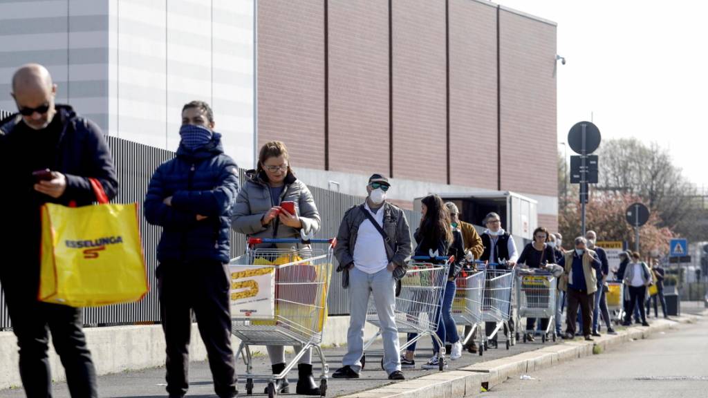 Kundinnen und Kunden warten vor einem Supermarkt in Italien auf Einlass.