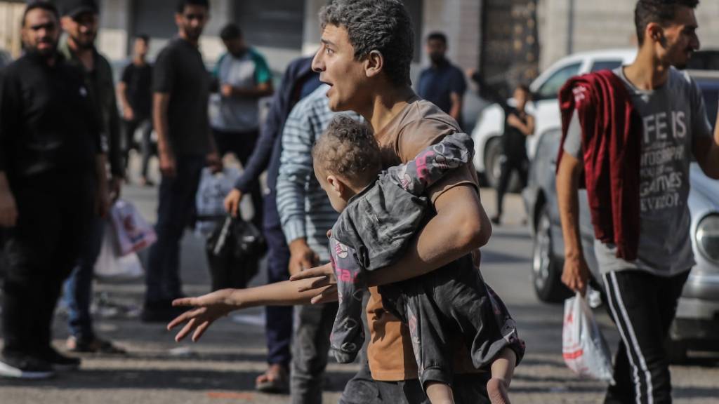 Ein Mann trägt nach einem israelischen Luftangriff auf Gaza-Stadt ein verletztes Kind auf dem Arm. Foto: Mohammed Abu Elsebah/dpa
