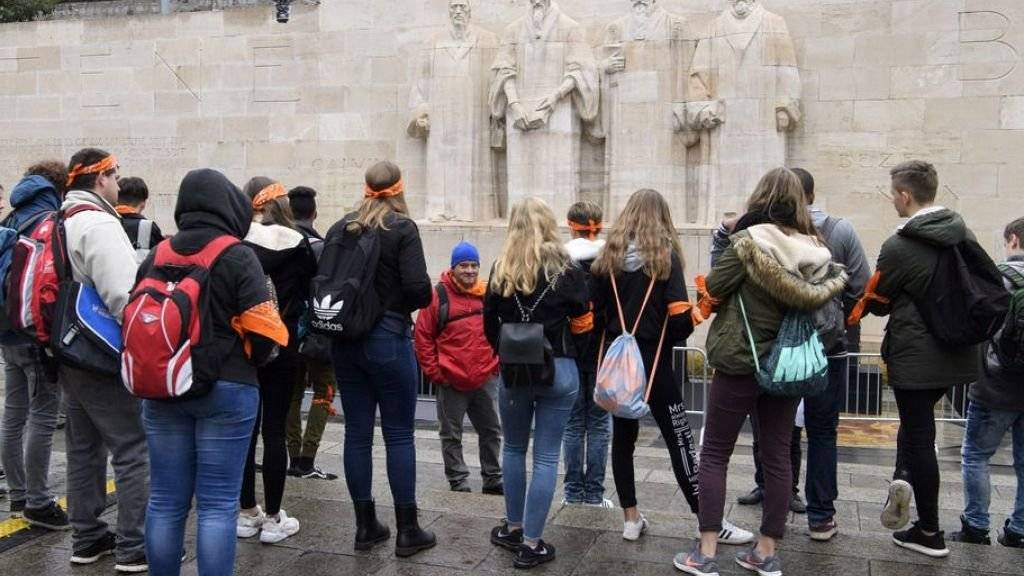 Die jugendlichen Protestanten und Protestantinnen aus der ganzen Schweiz informieren sich bei der Mauer der Reformatoren in Genf über die Rolle der Stadt während der Reformationszeit.
