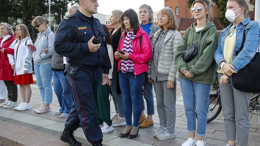 Ein Polizist bittet Demonstrantinnen in Minsk, den Ort zu verlassen. Foto: Dmitri Lovetsky/AP/dpa