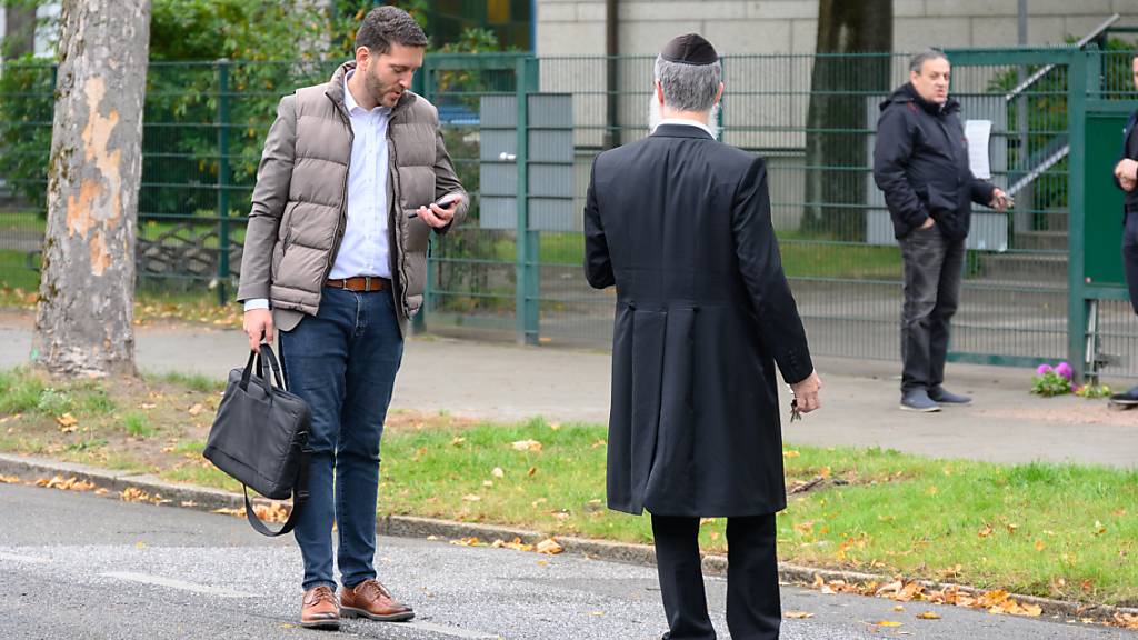 Philipp Stricharz (l), erster Vorsitzender der jüdischen Gemeinde Hamburg, steht mit Shlomo Bistritzky, Landesrabbiner von Hamburg, vor der Synagoge und schaut auf sein Handy. Ein Mann im Tarnanzug hatte einen Studenten mit einem Spaten angegriffen. Foto: Jonas Walzberg/dpa