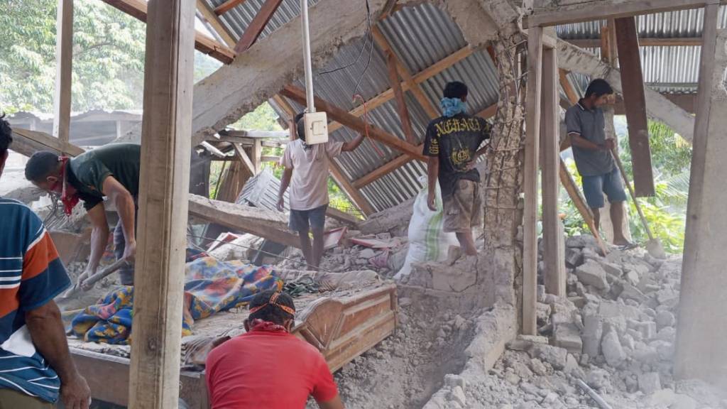 Menschen räumen die Trümmer eines durch ein Erdbeben beschädigten Hauses in Ost-Manggarai in der Provinz Ost-Nusa Tenggara weg. Foto: Kurniawan/AP/dpa