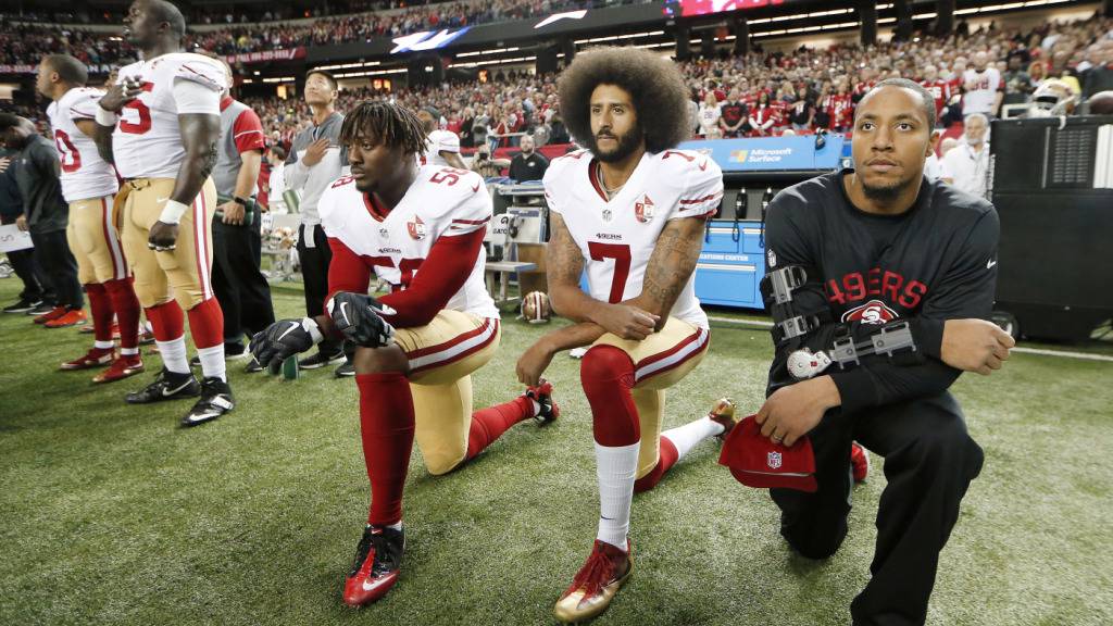Colin Kaepernick (Mitte), damals Quarterback der San Francisco 49ers, kniet am 18. Dezember 2016 vor der NFL-Partie gegen die Atlanta Falcons während der Nationalhymne nieder
