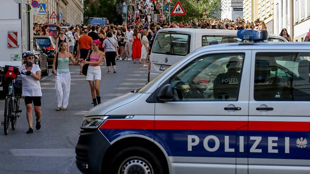 Ein Polizeiauto steht in der Nähe von versammelten «Swifties». Foto: Heinz-Peter Bader/AP/dpa