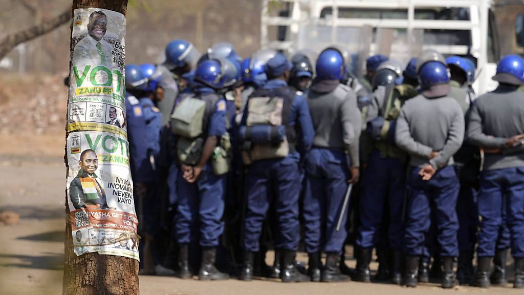 Heerscharen von Polizisten, bewaffnet mit Schlagstöcken, Tränengaskanistern und teilweise mit Gewehren, waren neben dem Ergebniszentrum zu sehen, als die Simbabwer nach Schließung der Wahllokale am 24.08.2023 gespannt auf das Ergebnis der Parlamentswahlen warteten. Regionalen Wahlbeobachtern zufolge hat die Präsidentschafts- und Parlamentswahl in Simbabwe teils nicht den gesetzlichen Anforderungen entsprochen. Foto: Tsvangirayi Mukwazhi/AP/dpa