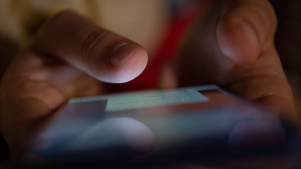 Ein Smartphone wird gehalten. Minderjährige in Großbritannien, deren selbst gemachte Nacktfotos oder -videos im Internet kursieren, können sich künftig per Online-Dienst Hilfe zum Löschen der Aufnahmen holen. (Symbolbild)