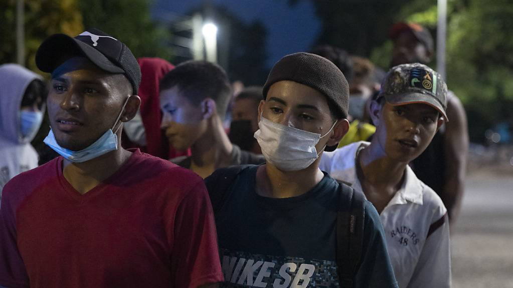 Migranten aus Honduras stehen nebeneinander und warten auf Hilfe auf ihrem Weg in Richtung USA. Foto: Moises Castillo/AP/dpa