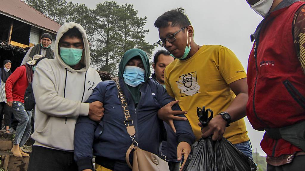 Eine Angehörige eines Opfers des Vulkanausbruchs wird von Familienmitgliedern beim Gehen unterstützt. Foto: Ade Yuandha/AP/dpa