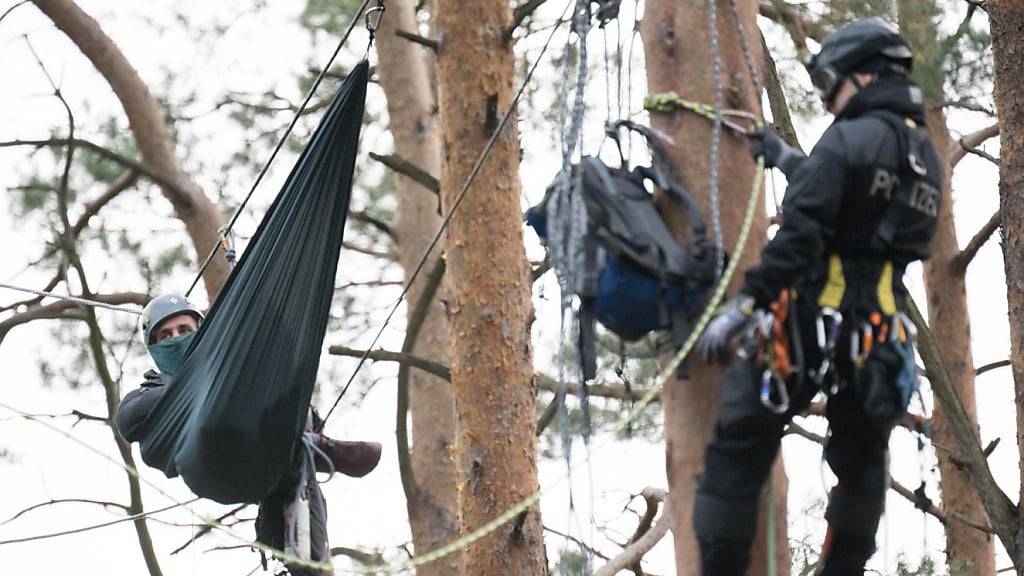 Ein Aktivist hängt in einem Waldstück nahe der Tesla-Fabrik nahe Berlin beim Protestcamp der Initiative «Tesla stoppen» hinter einem Polizeibeamten. (Archivbild)