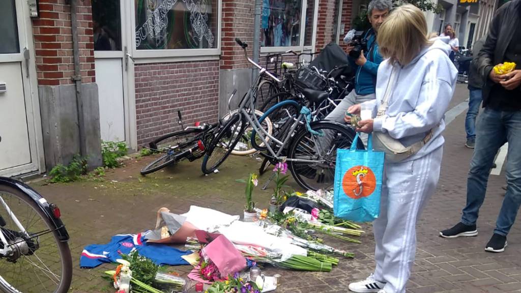 Eine Frau steht vor Blumen am Tatort, nachdem dort am Abend des 6. Juli der niederländische Journalist de Vries niedergeschossen wurde.