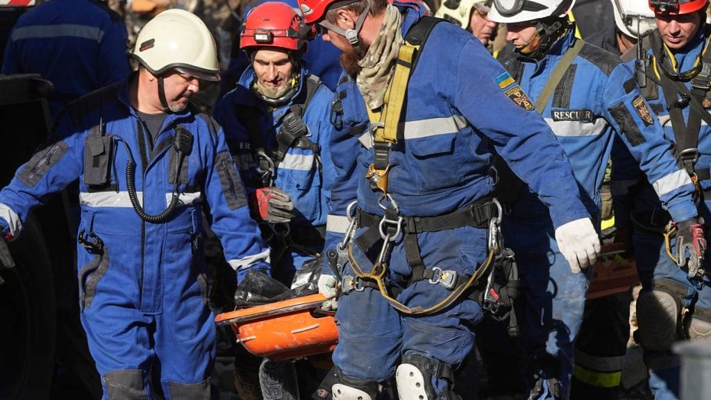Feuerwehrleute tragen die Leiche eines Opfers aus einem beschädigten Gebäude nach einem russischen Angriff. Foto: Efrem Lukatsky/AP/dpa