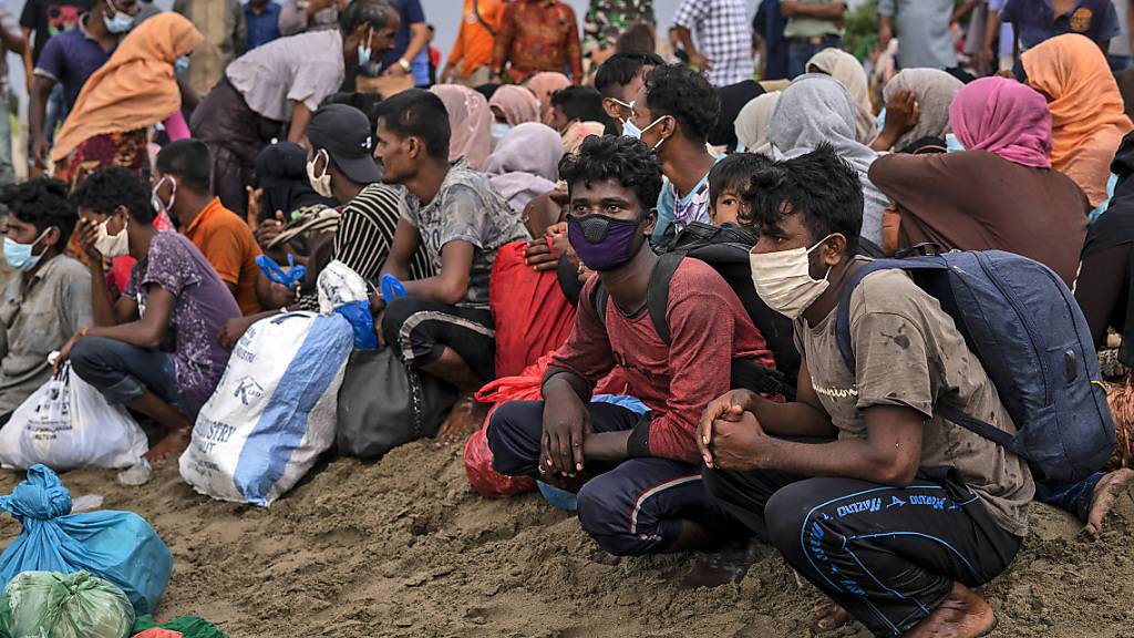 Geflüchtete Rohingya sitzen am Strand der Provinz Lancok, nachdem sie mit einem Boot dort angekommen sind. Indonesische Fischer entdeckten die hungernden und geschwächten Rohingya-Muslime auf dem Holzboot, das vor Indonesiens nördlichster Provinz Aceh trieb. Foto: Zik Maulana/AP/dpa