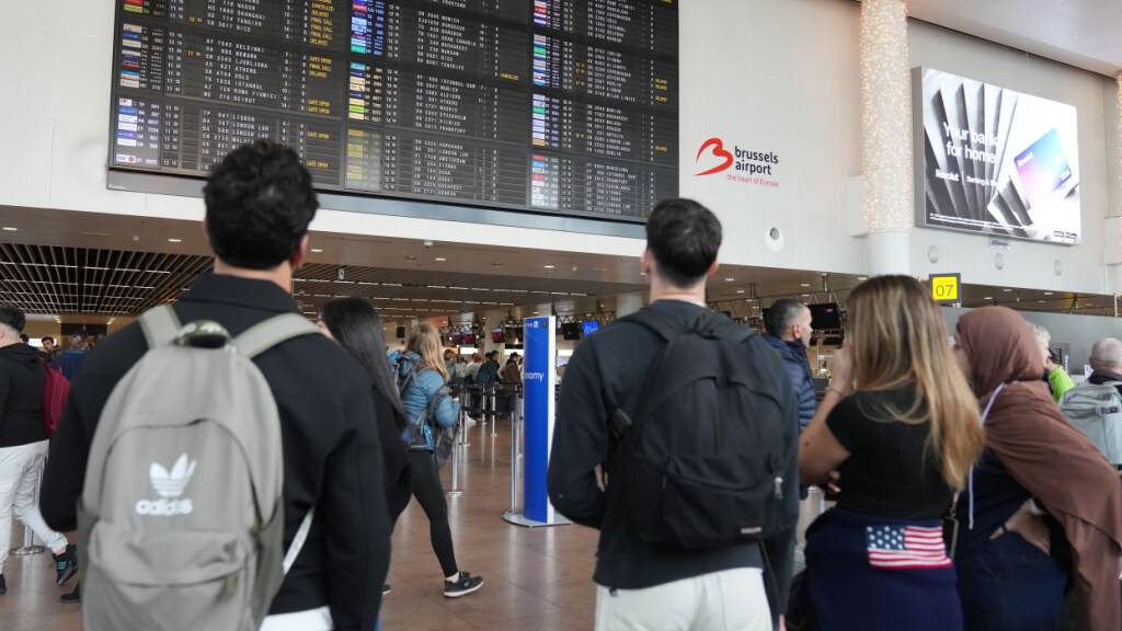 Passagiere schauen auf eine Abflugtafel, nachdem mehrere Flüge gestrichen wurden. Foto: Virginia Mayo/AP/dpa