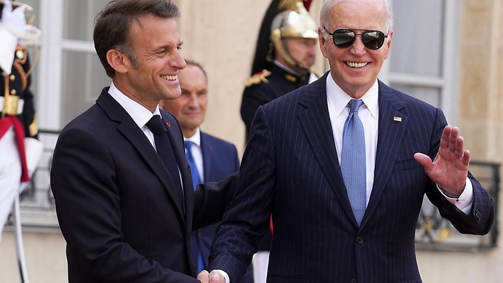 Der US-Präsident Joe Biden (r) winkt, während er dem französischen Präsidenten Emmanuel Macron nach ihren Gesprächen im Elysee-Palast die Hand reicht. Foto: Michel Euler/AP/dpa