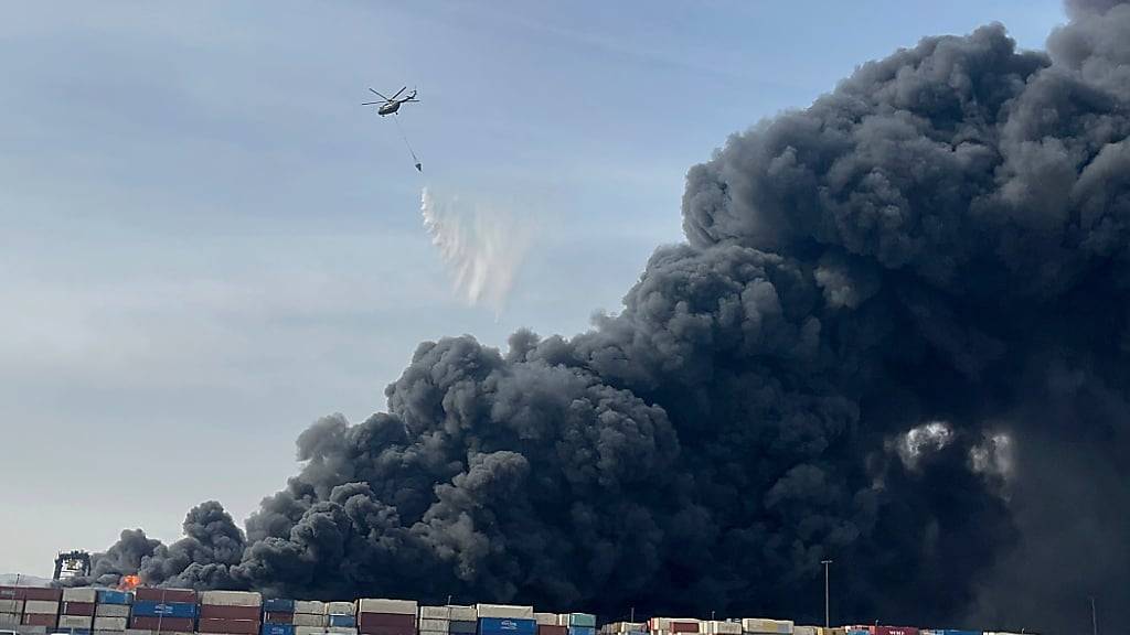 HANDOUT - Auf diesem von der iranischen Studenten-Nachrichtenagentur ISNA via AP zur Verfügung gestellten Foto wirft ein Hubschrauber Wasser auf das Feuer und den schwarzen Rauch, nachdem eine massive Explosion einen Hafen in der Nähe der südlichen Hafenstadt Bandar Abbas erschüttert hat. Foto: Razieh Pudat/Iranian Students' News Agency, ISNA/AP/dpa - ACHTUNG: Nur zur redaktionellen Verwendung und nur mit vollständiger Nennung des vorstehenden Credits