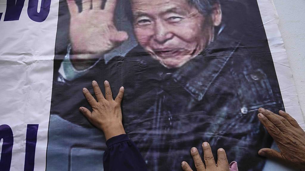 Unterstützer des inhaftierten ehemaligen Präsidenten Alberto Fujimori berühren ein Schild mit seinem Foto vor dem Gefängnis, in dem er inhaftiert ist. Foto: Martin Mejia/AP/dpa
