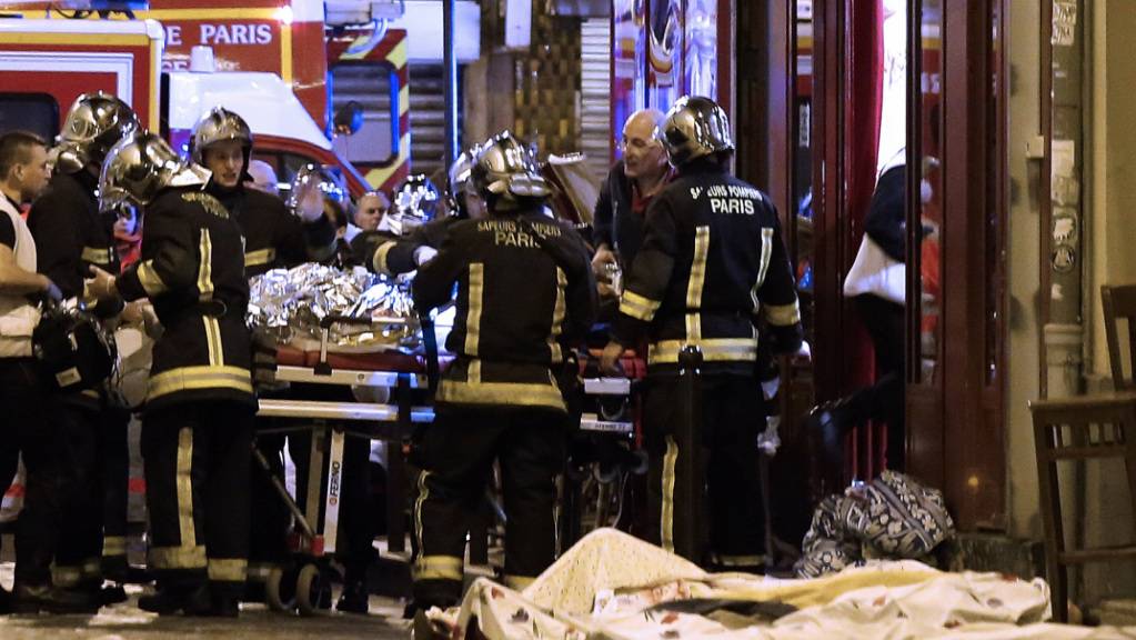 ARCHIV - Rettungskräfte versorgen die Opfer vor einem Café im 10. Bezirk. Bei den Terroranschlägen des Islamischen Staates im November 2015 in Paris starben 130 Menschen, Hunderte wurden verletzt. Foto: Jacques Brinon/AP/dpa