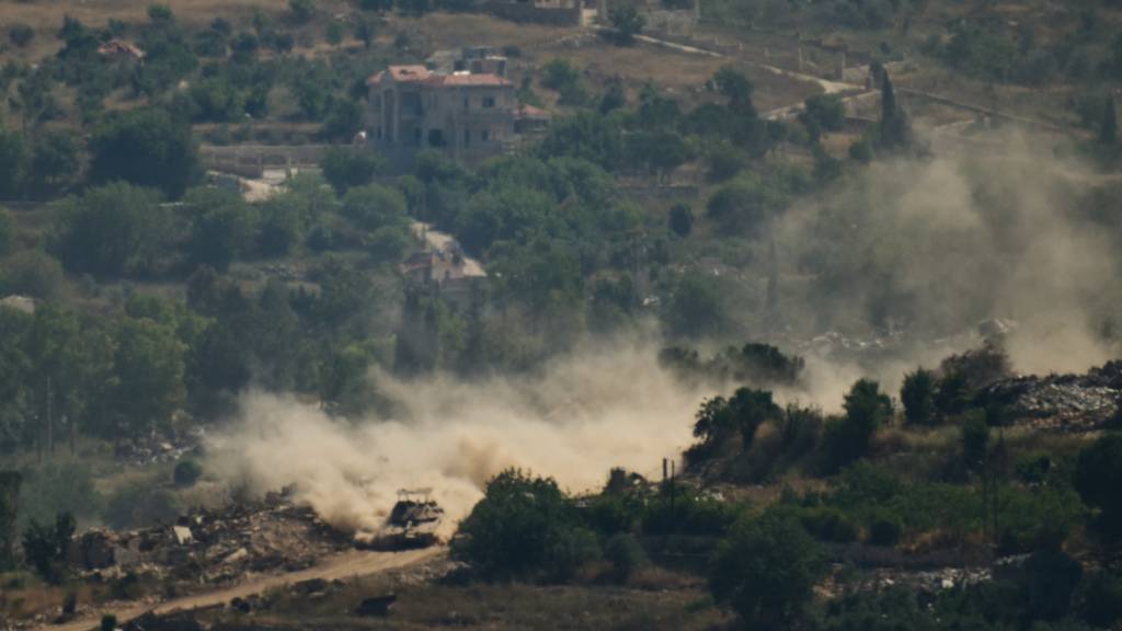 Ein israelischer Panzer fährt an zerstörten Gebäuden im Südlibanon vorbei, aufgenommen aus Nordisrael. Foto: Leo Correa/AP/dpa