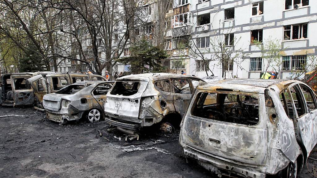 Zerstörte Autos stehen vor einem mehrstöckigen Wohnhaus, das durch die Trümmer einer russischen Angriffsdrohne beschädigt wurde. Foto: Mykola Miakshykov/ukrin/dpa