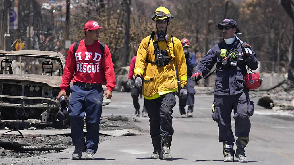 Mitglieder eines Such- und Rettungsteams gehen in Lahaina, Hawaii, eine Straße entlang. Foto: Rick Bowmer/AP/dpa