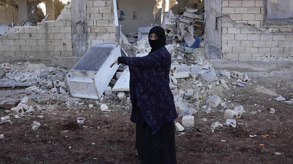 Eine Frau vor einem zerstörten Gebäude in Syrien.