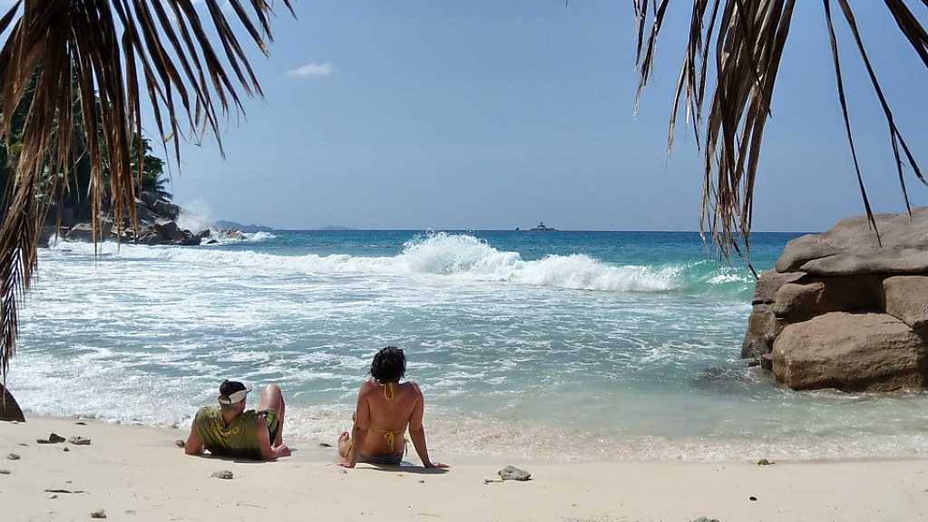 Touristen liegen am Strand der Seychelleninsel La Digue.
