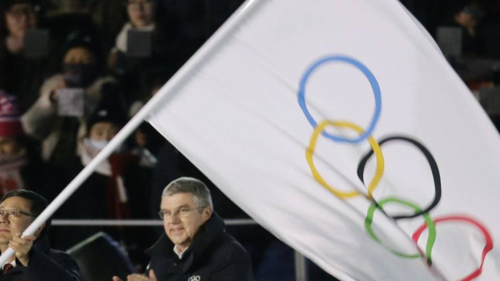 Chen Jining, der Stadtpräsident von Peking, schwenkt vor den Augen von IOC-Präsident Thomas Bach die olympische Flagge