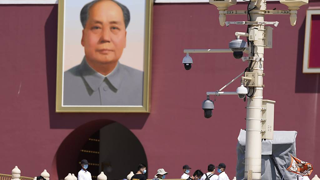 Sicherheitskräfte in Zivil beobachten, wie Touristen das Tian'anmen-Tor am 32. Jahrestag der blutigen Niederschlagung der Demokratiebewegung besuchen. Zum Jahrestag des Massakers am 4. Juni 1989 in China haben Familien der Opfer eine gerechte Aufarbeitung dieses dunklen Kapitels der chinesischen Geschichte gefordert. Foto: Ng Han Guan/AP/dpa