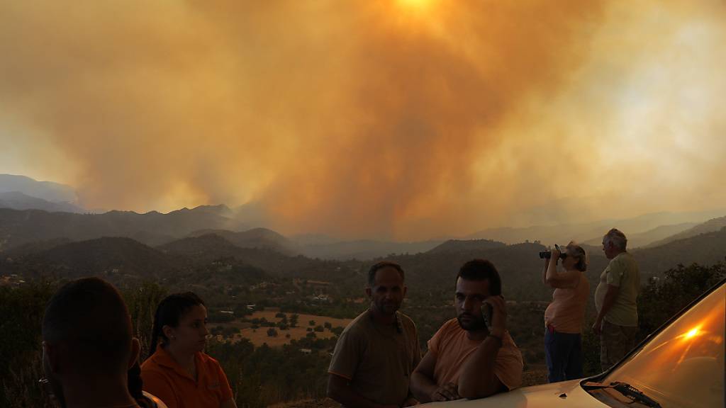 Anwohner beobachten ein Feuer in der Bergregion von Larnaca. Foto: Petros Karadjias/AP/dpa